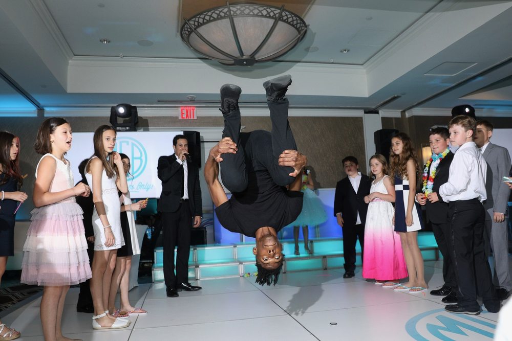 Dancer flipping mid-air as Bar Mitzvah guests look on