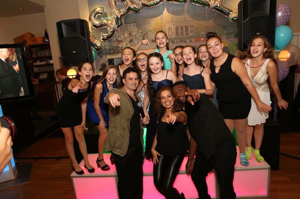 Guests cheering on a lit LED stage with Jerry Laskin's MC and dance crew