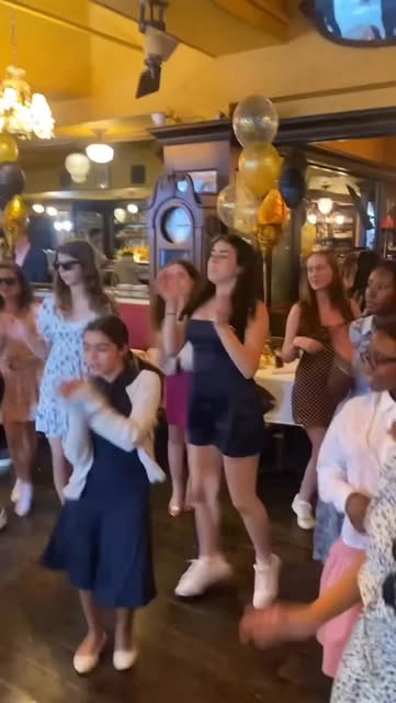 Teens dancing in a restaurant party room with balloons