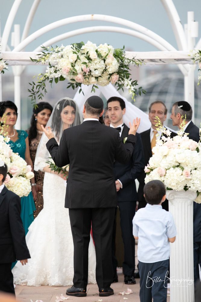 Bride and groom under a floral chuppah at a rooftop wedding